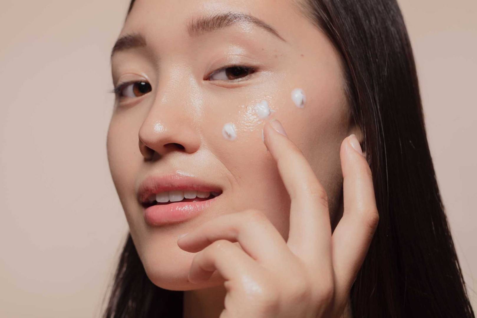 Close up of a young woman applying moisturizer to her face