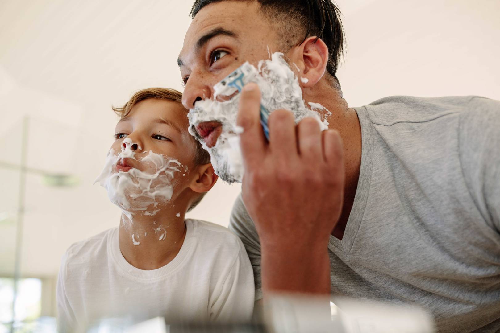 Funny father and son shaving in bathroom