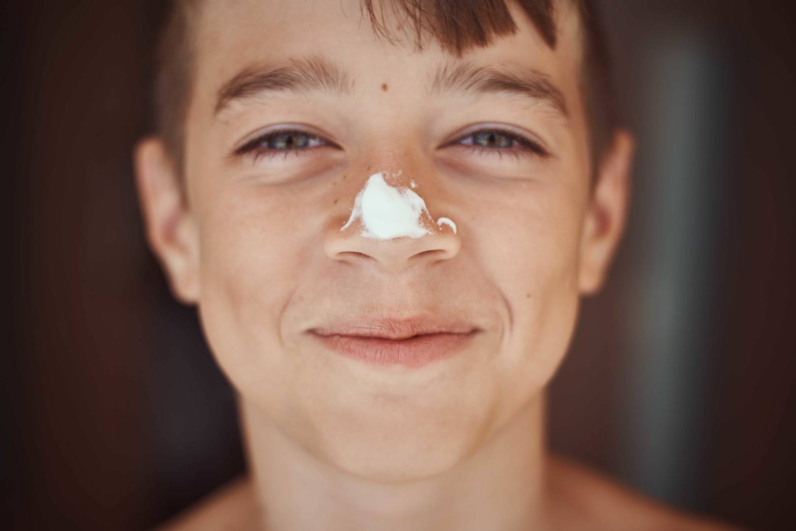 Smiling boy with sunscreen cream on his nose