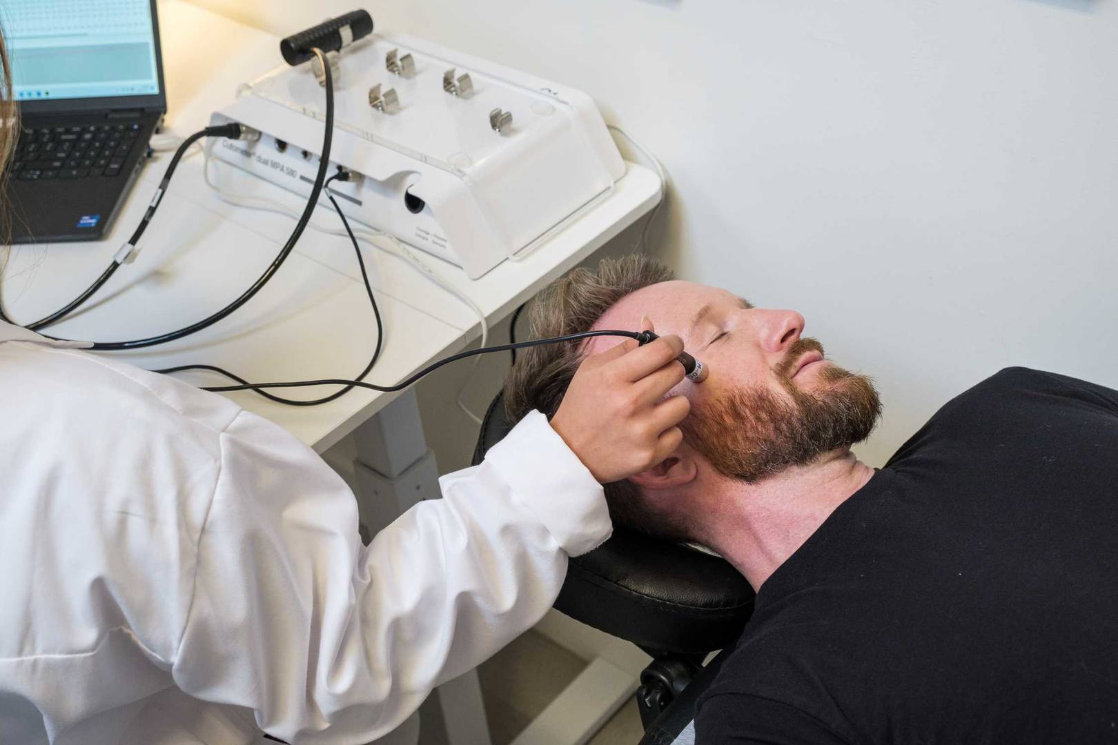 Male clinical testing panelist getting tested on cheek with machine