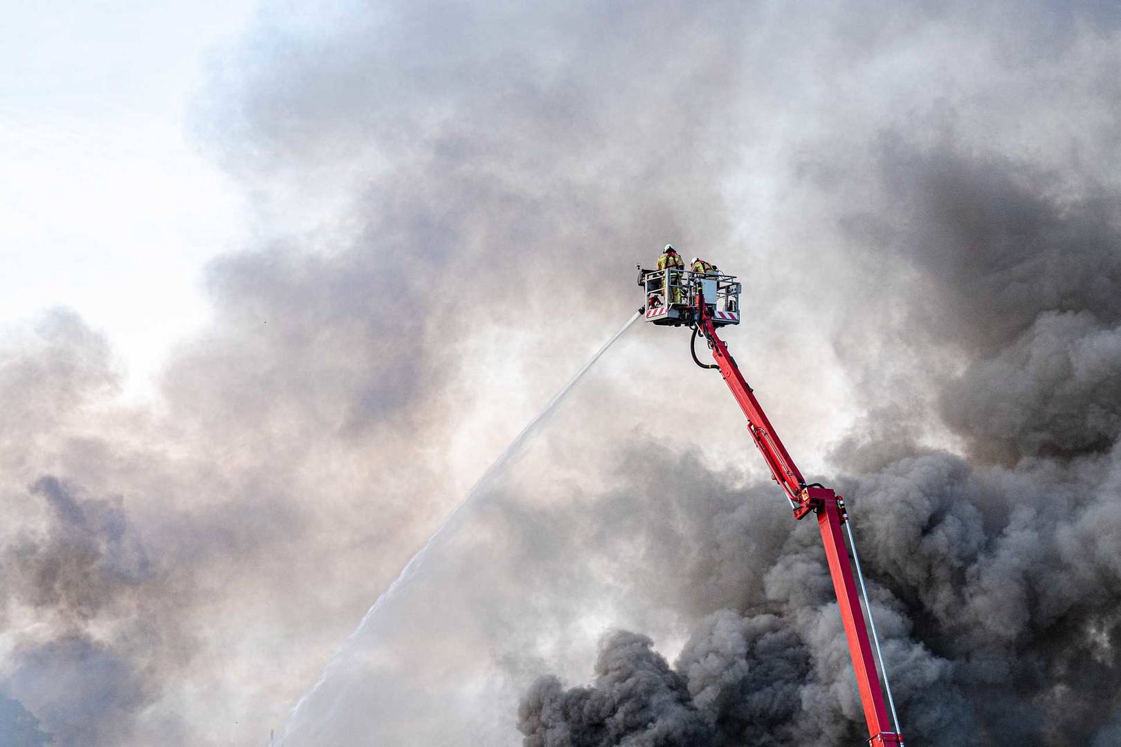 Firemen in the air putting our a fire with smoke-filled air all around them