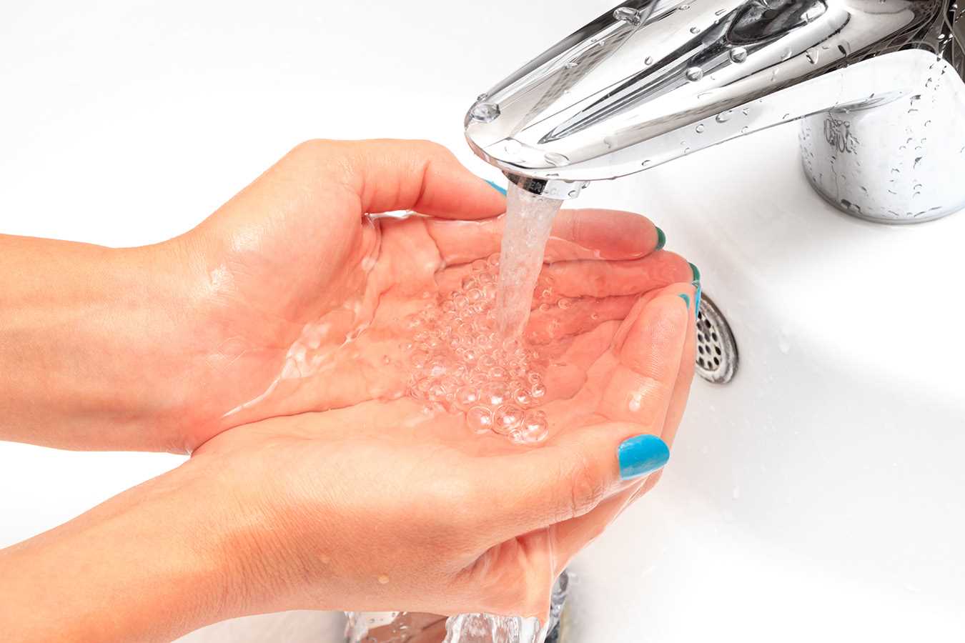 Mãos a serem lavadas com água corrente de uma torneira, simbolizando a vigilância da qualidade da água.