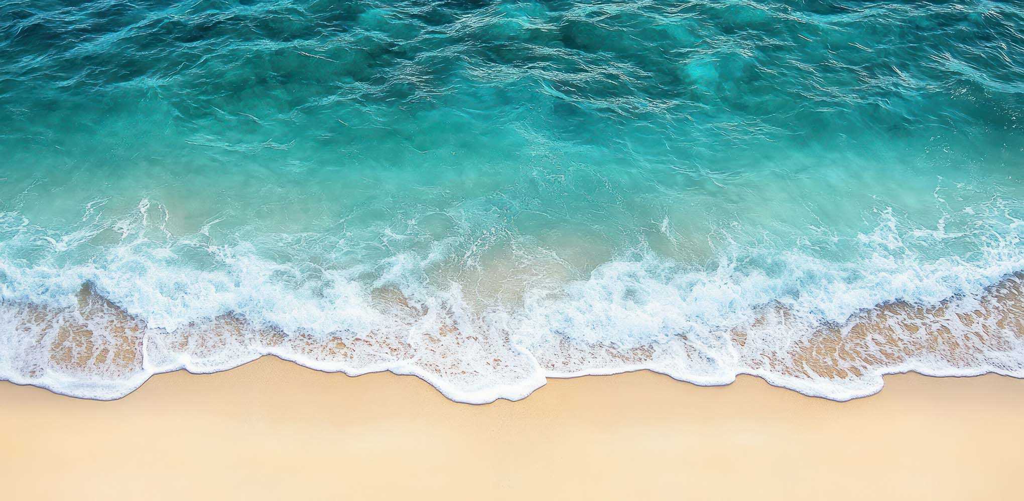 Praia com água azul-turquesa a chegar à areia, representando águas naturais salinas.