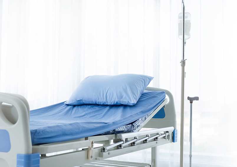 Cama hospitalar preparada num quarto clínico com sistema de soroterapia.