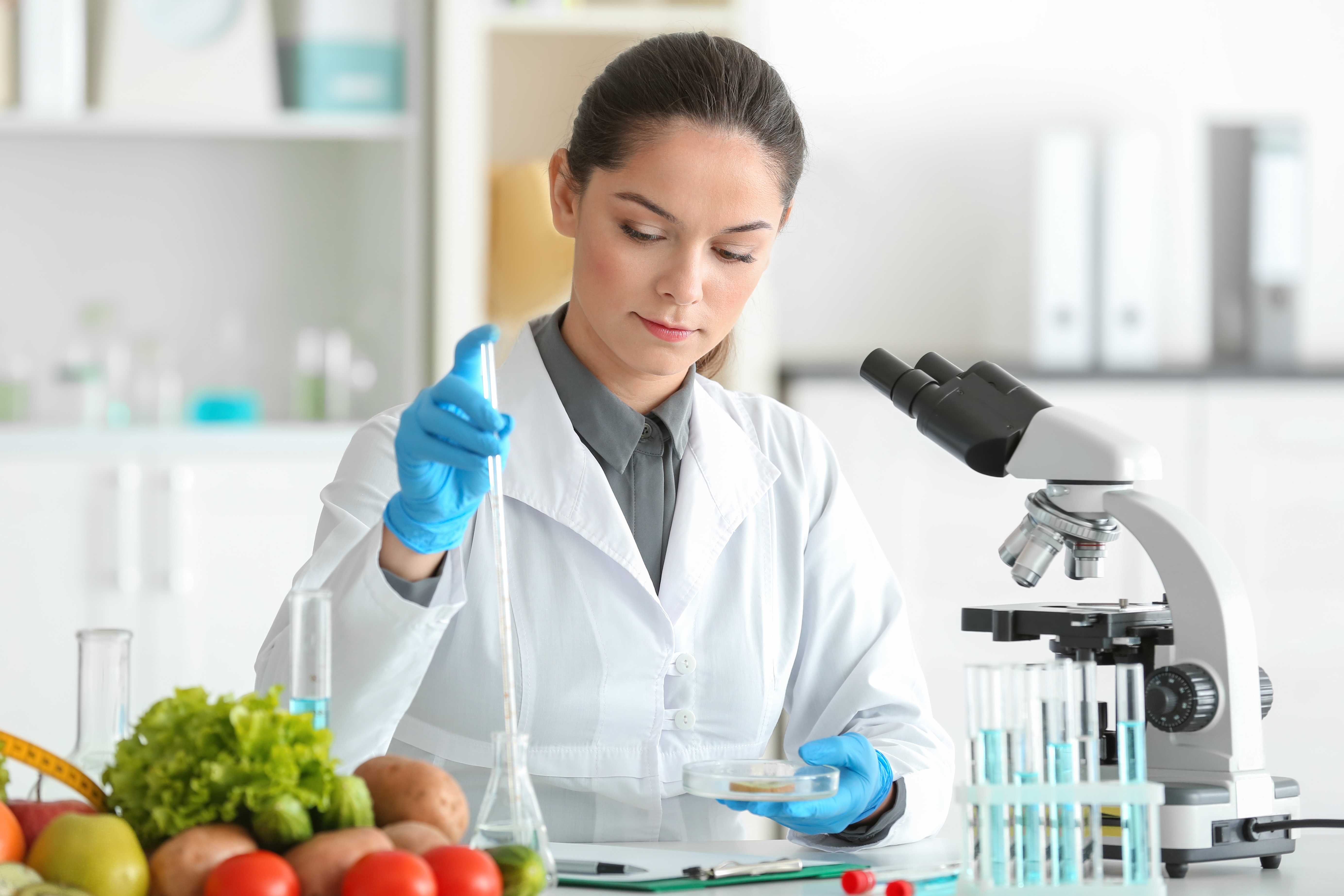 Mladá nutriční specialistka testující vzorky potravin v laboratoři.