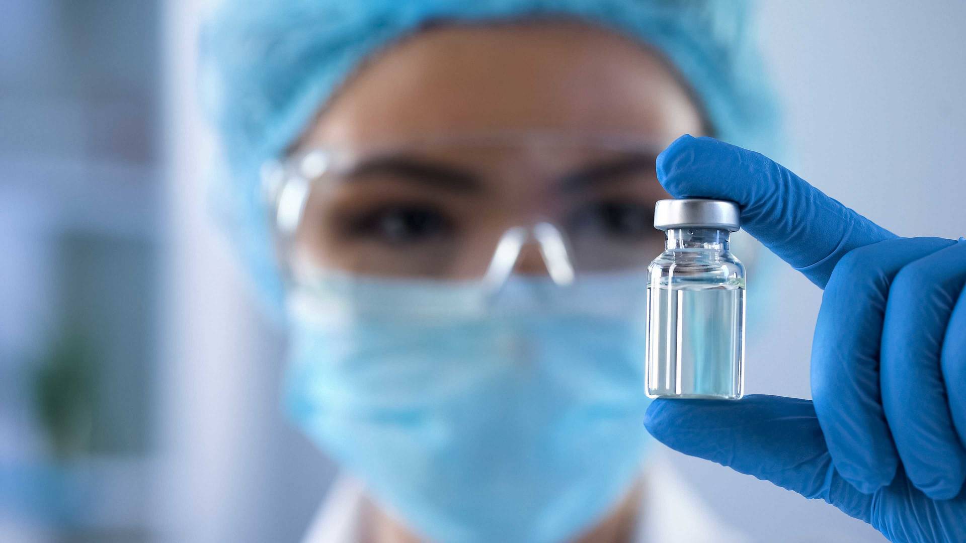Person i laboratoriemiljö håller en steril injektionsflaska med vätska, kopplat till sterilitetsprovning.