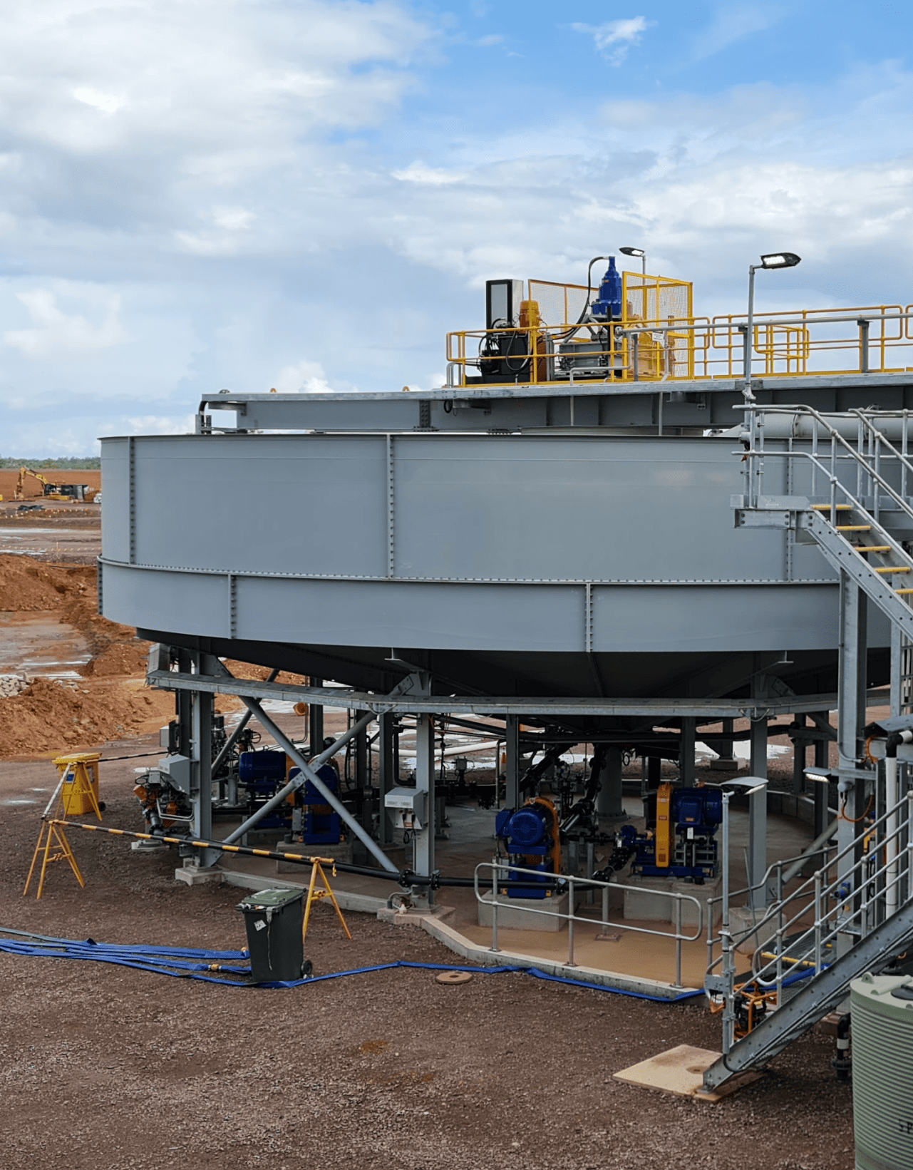 Industrial thickener tank on elevated steel supports with pumps underneath